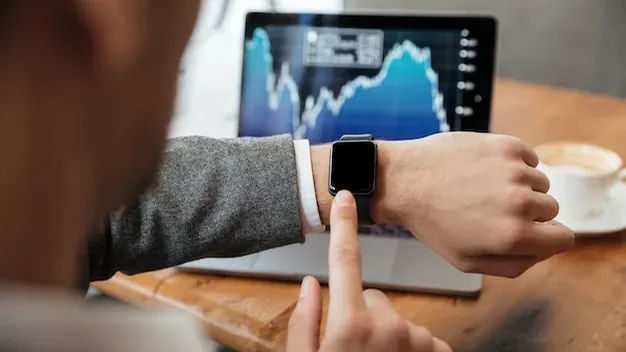 Cropped image of businessman sitting by the table in cafe and analyzing indicators on laptop computer while us