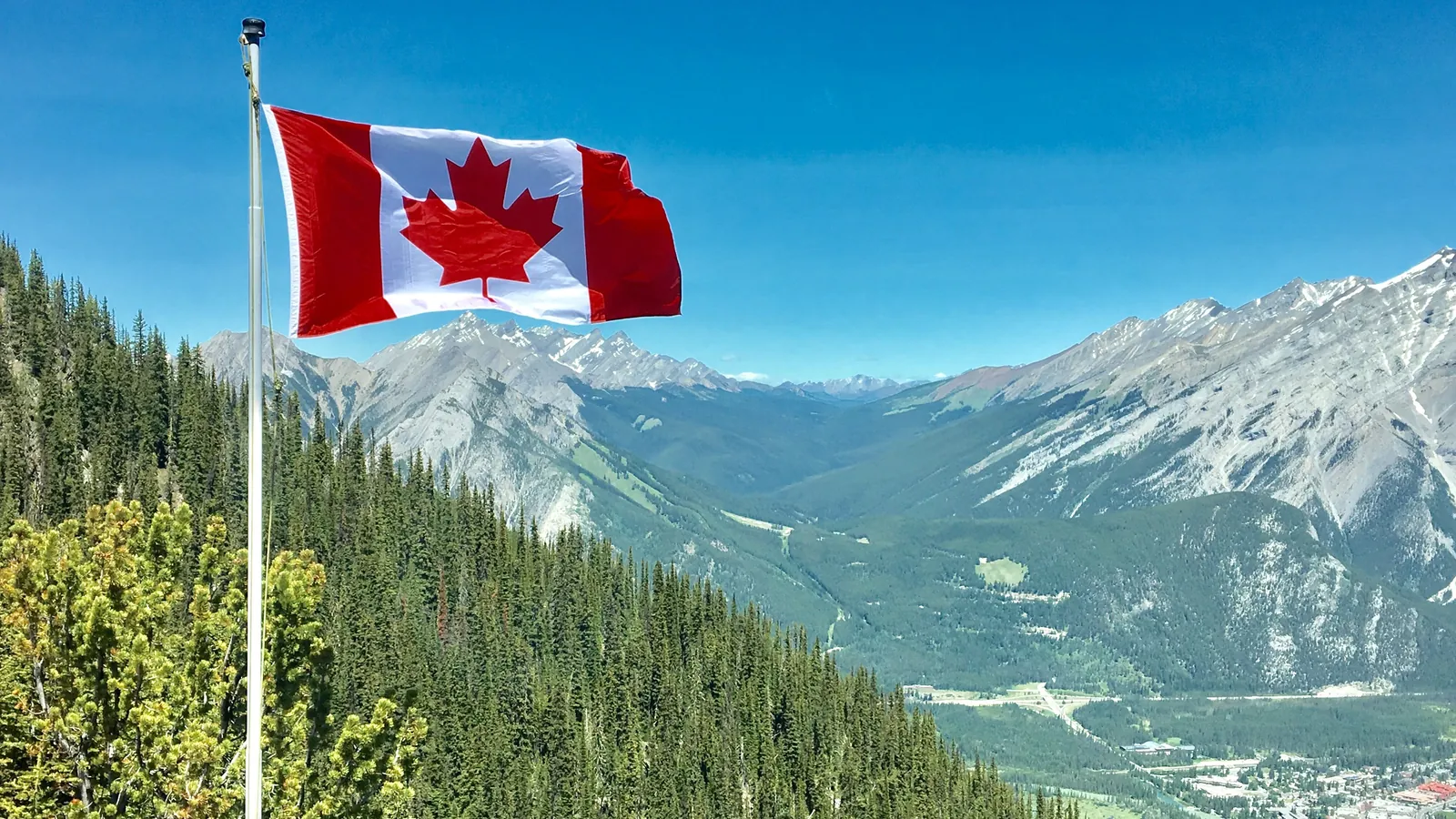Red maple leaf flag overlooking forested mountains
