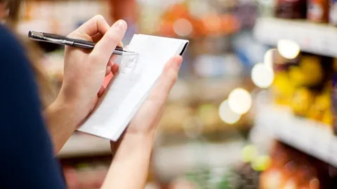 Shopper writing on a notepad in a supermarket aisle