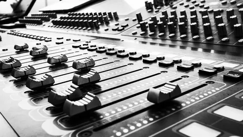 Black and white close-up of mixing desk sliders and knobs