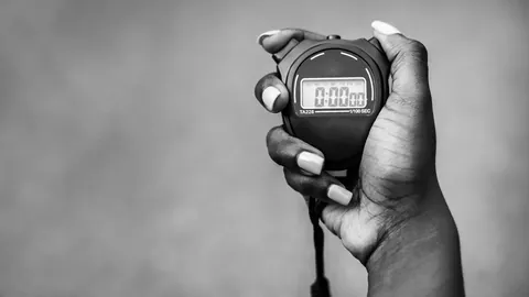 Hand holding a digital stopwatch, in black and white