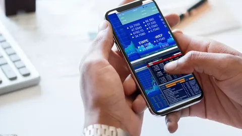 Hands holding a smartphone showing a trading app with charts