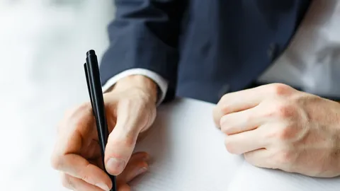Businessman writing notes with a pen at a desk