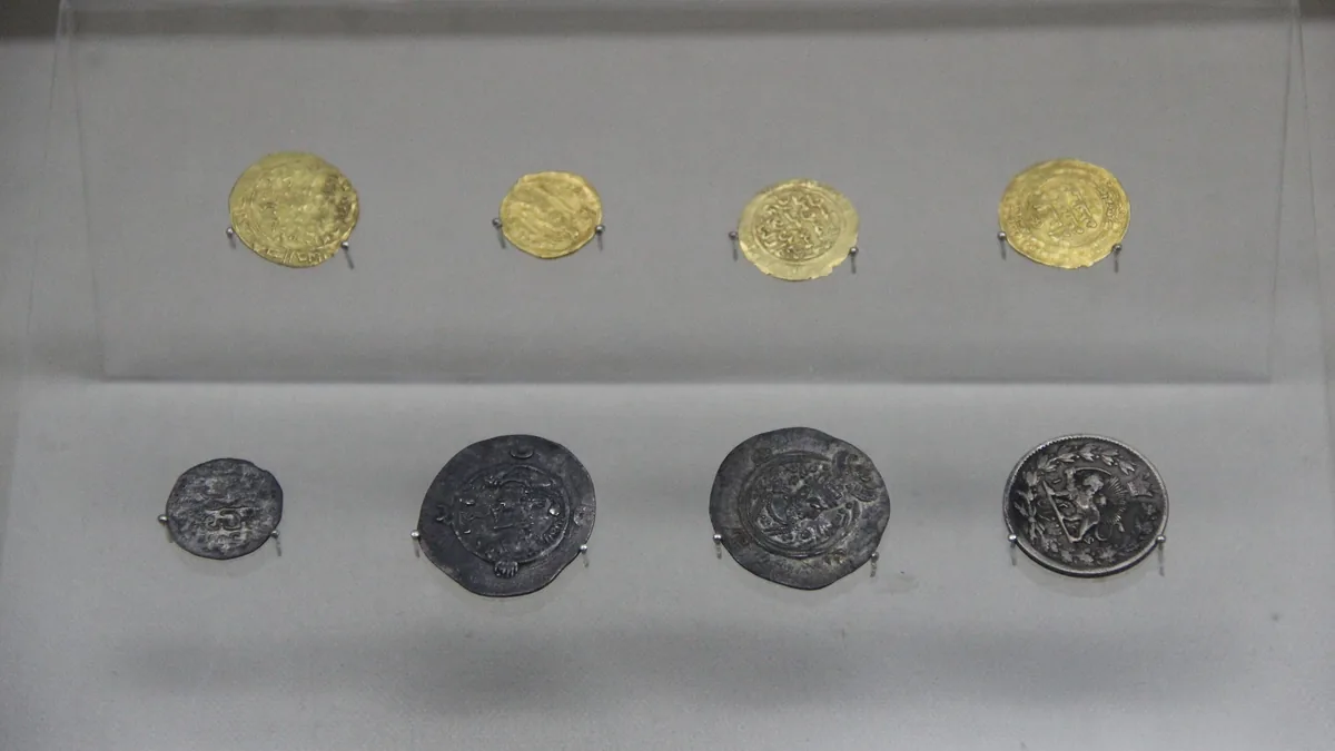 A museum row of gold coins above a row of silver coins from the Yuan dynasty