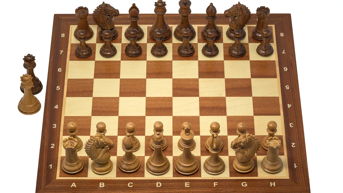 A wooden chess set arranged for the opening position, seen from the side
