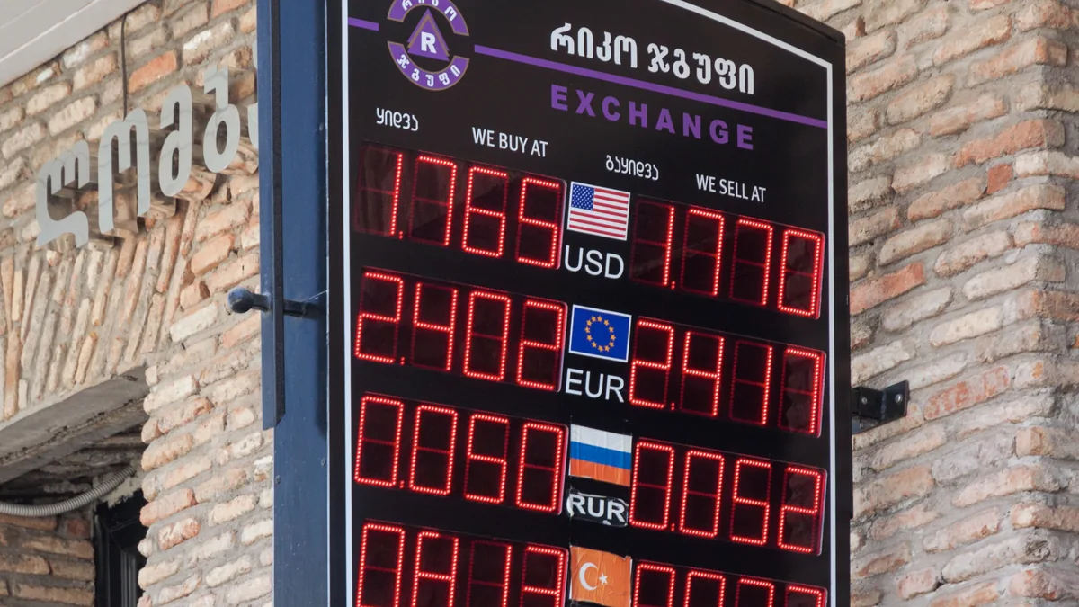 An electronic currency exchange board showing separate buy and sell rates for four currencies