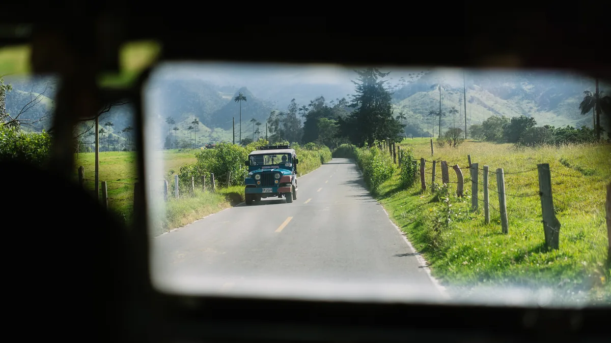 A country road seen in a car’s rear-view mirror