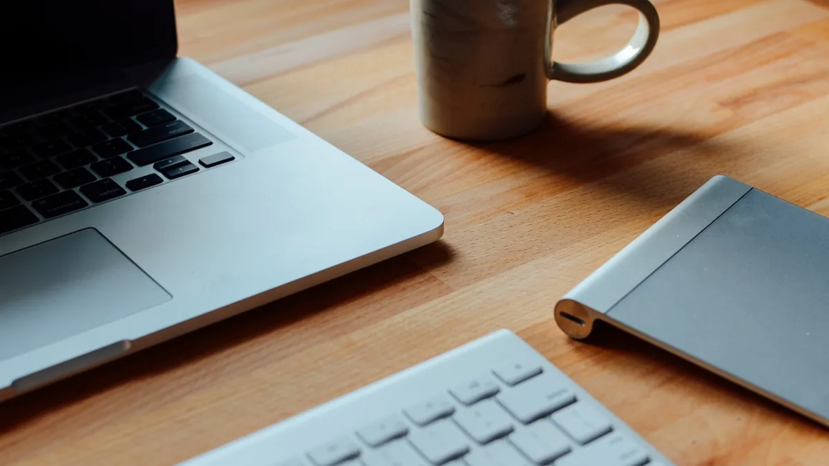 An open laptop and a mug on a plain desk