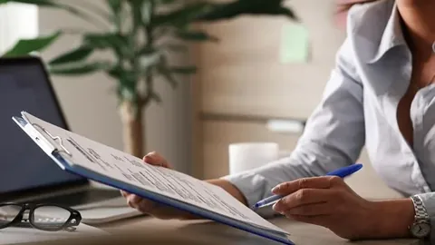 Unrecognizable female entrepreneur analyzing business reports while working on paperwork in the office