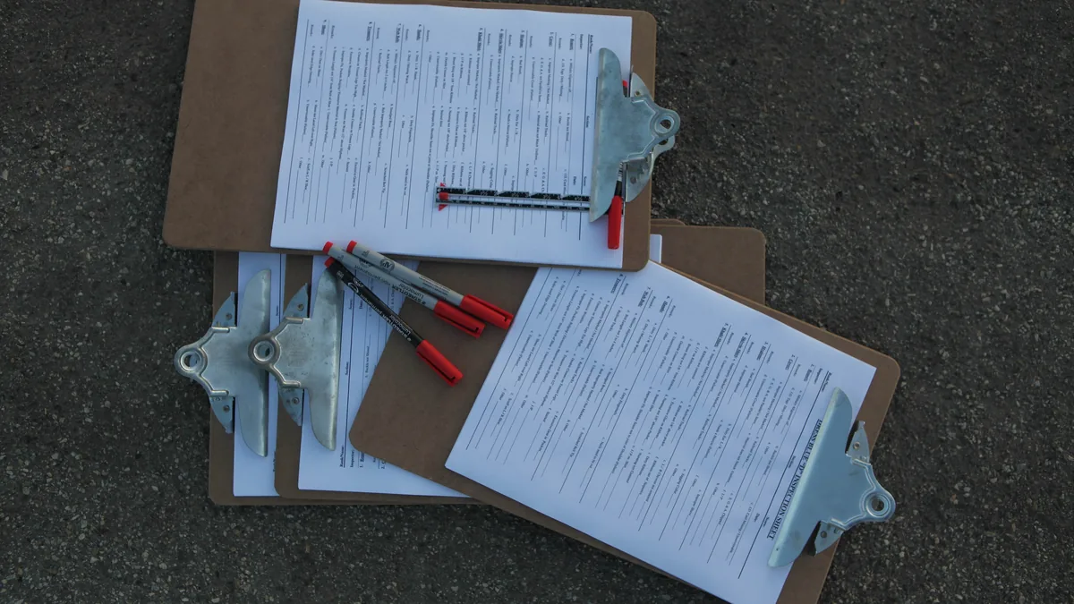Checklists and red pens laid out on clipboards on a table