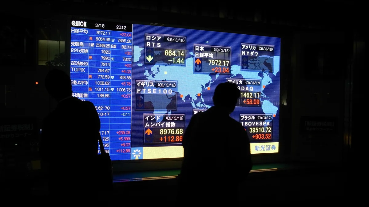 A passer-by silhouetted against an electronic stock price board in Tokyo