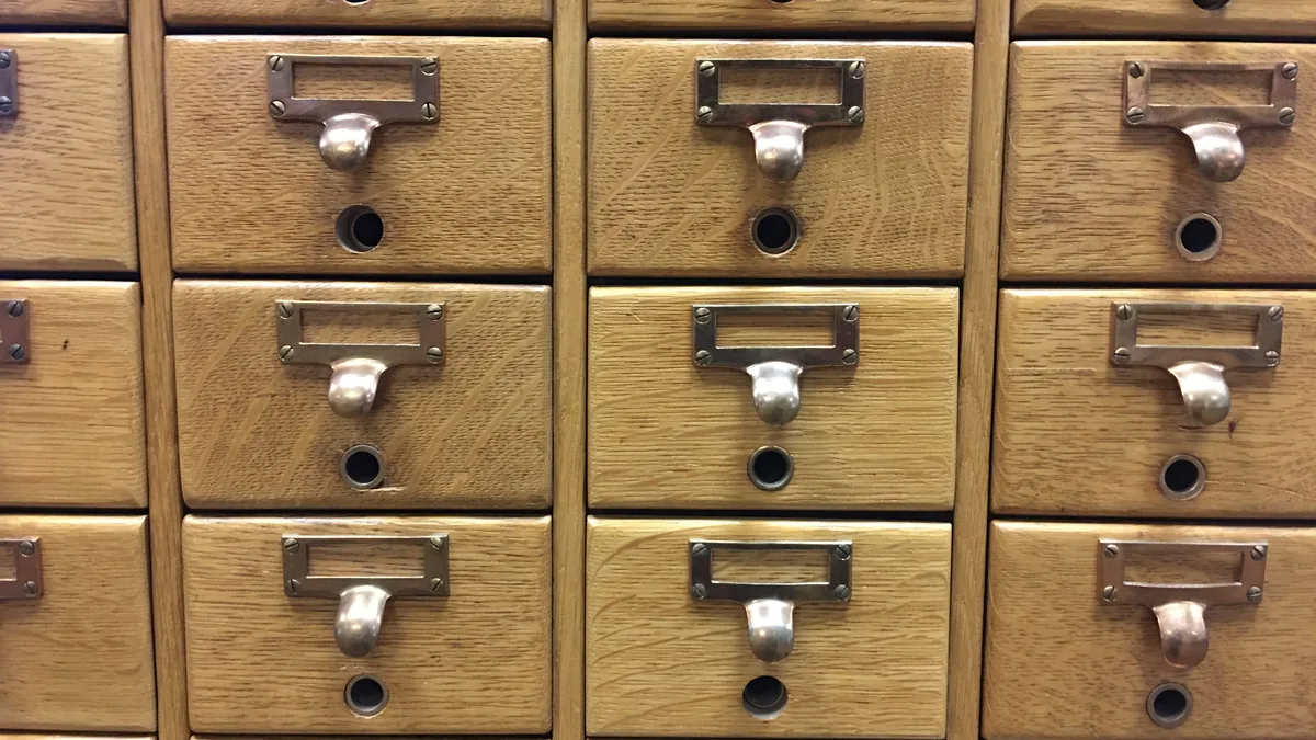Rows of wooden library card catalogue drawers with metal label holders