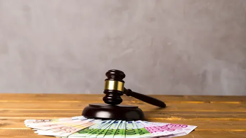 Judge’s gavel resting on euro banknotes on a wooden desk