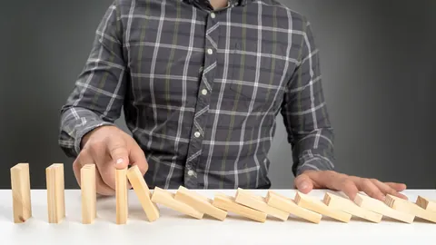Hand stopping a row of falling dominoes