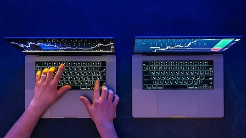 Man working on two laptops stock market trading investments top view