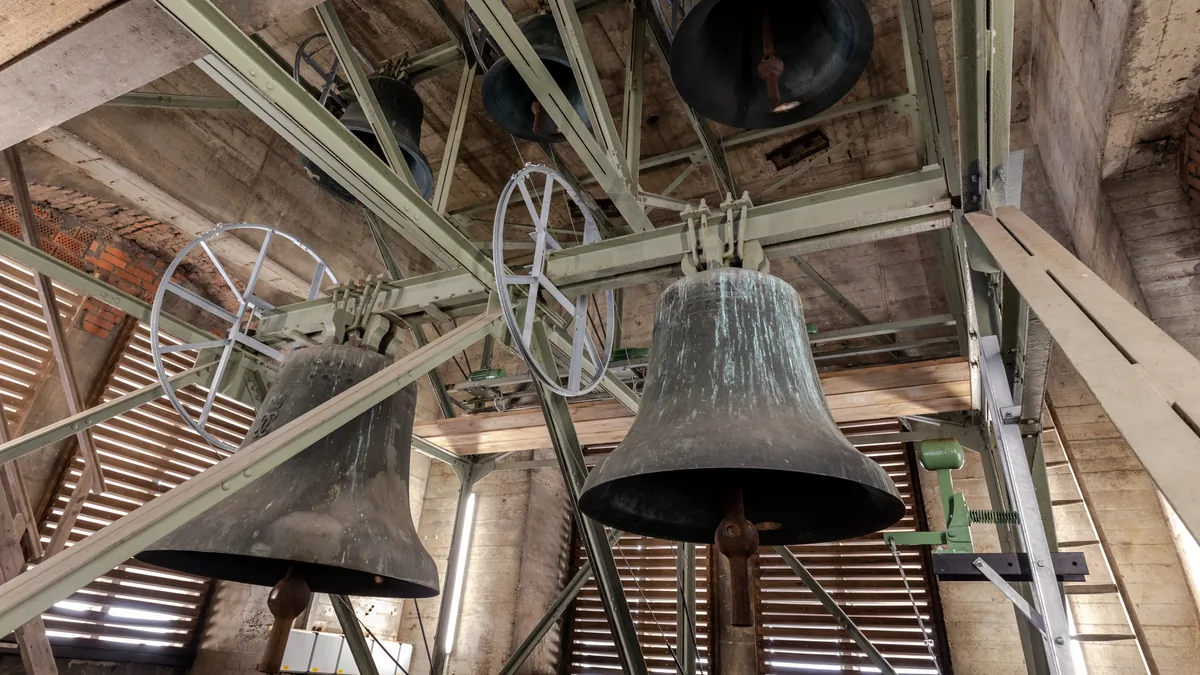 Two large bronze bells hanging in a church tower
