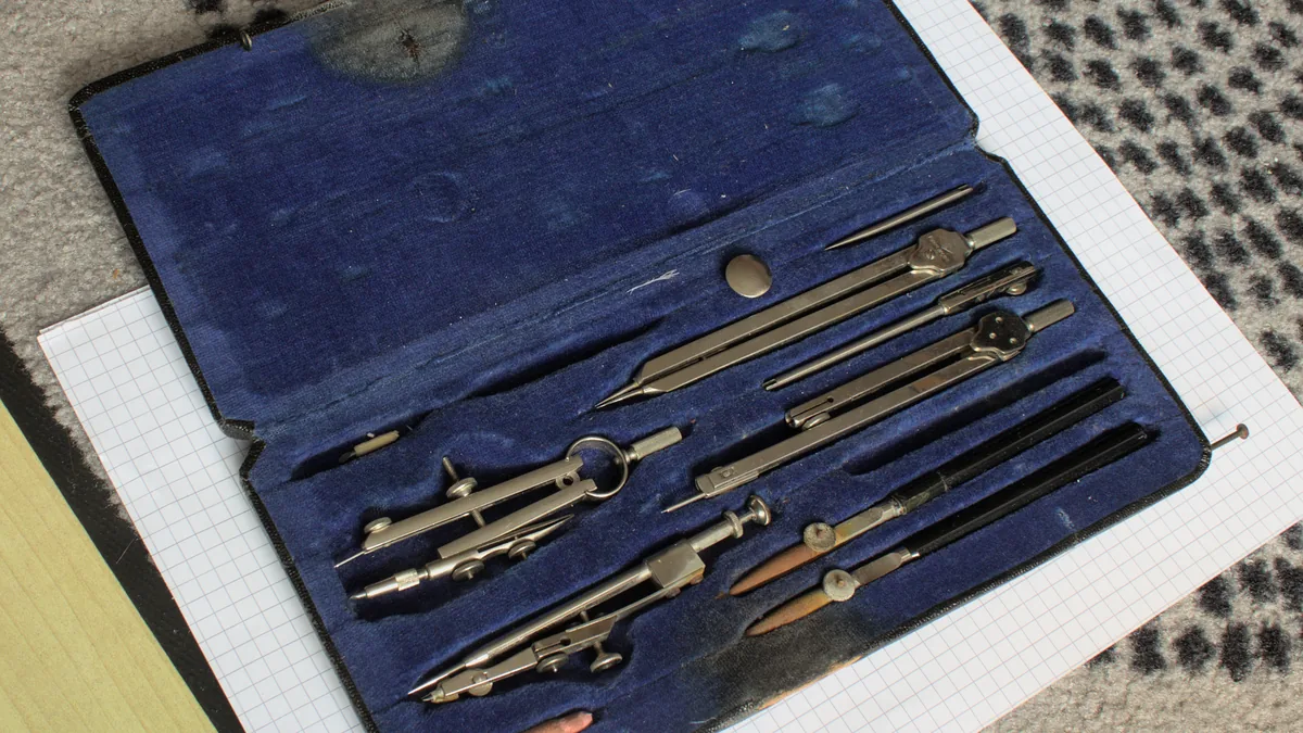 A drafting instrument set with compasses and dividers laid out in a velvet case