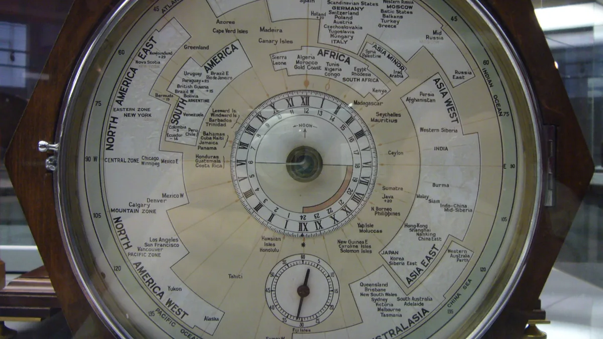 A world clock showing a map of the time zones around a brass-ringed dial