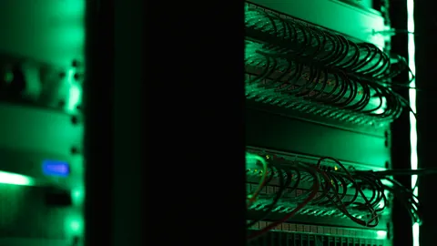 Server rack lit green in a dark room