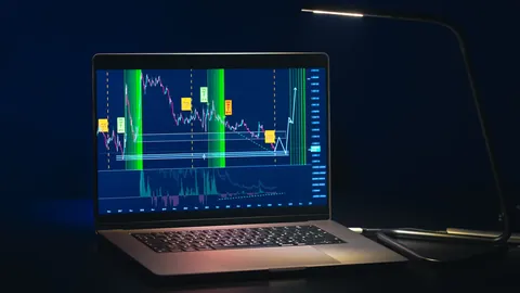 Laptop screen showing a trading chart in a dark room