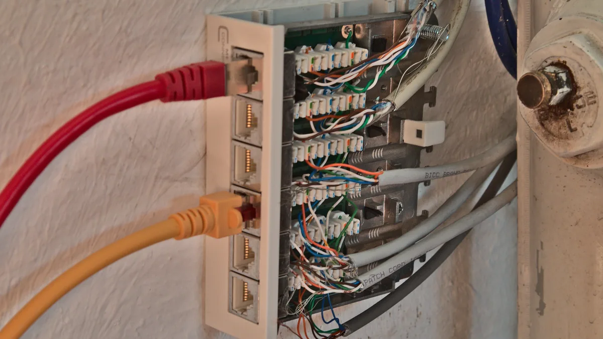 Red and yellow network cables plugged into a wall-mounted patch panel