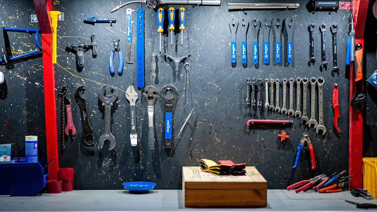 Wall of hand tools hanging on a dark pegboard