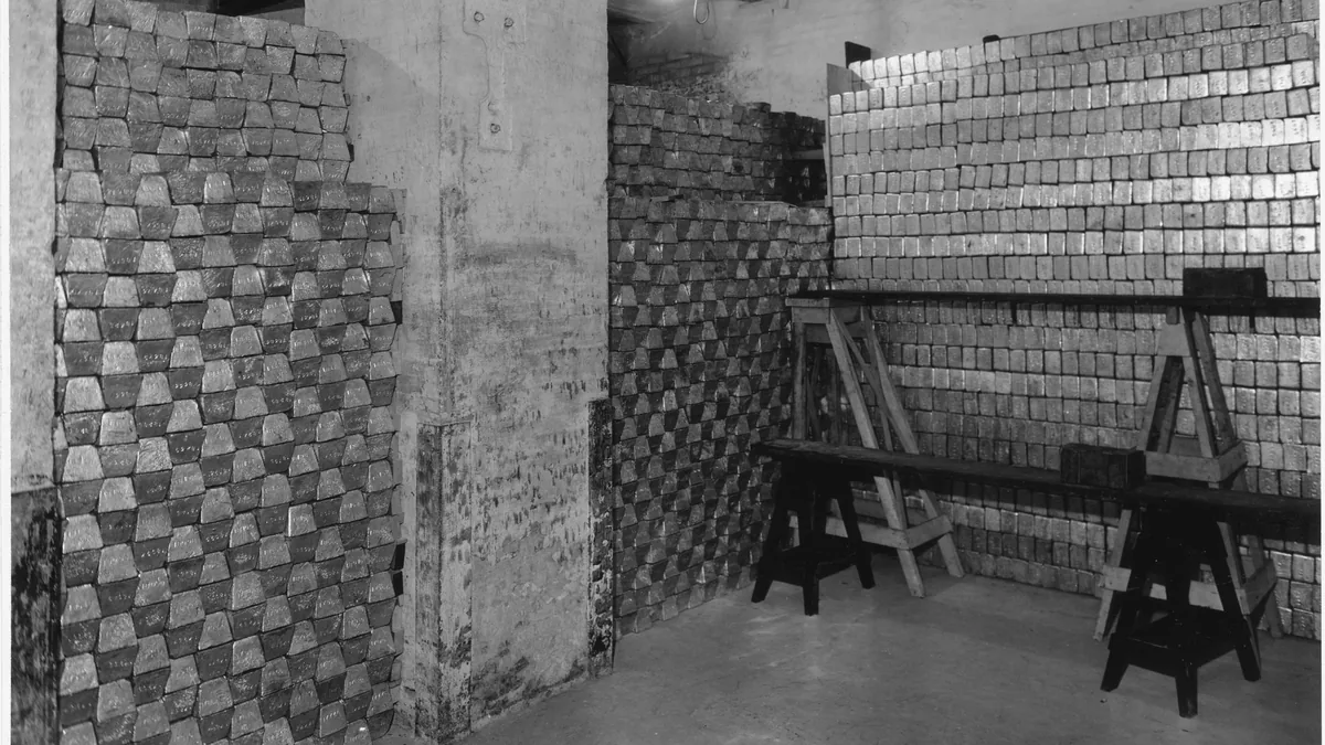 Rows of gold bars stacked inside a vault