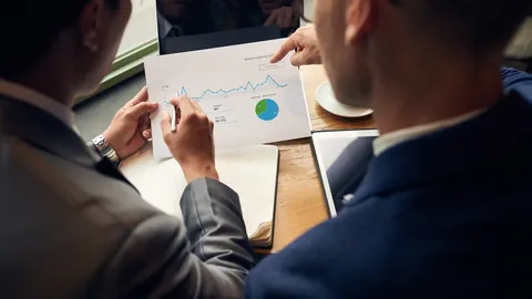 Businesspeople pointing at printed charts on a table